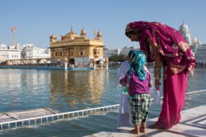 Inde, sur le bord de l'eau une mère et son enfant parlent à une autre personne